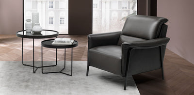 Luxury leather armchair in black on a wooden floor with a pale grey rug and a modern two tiered coffee table to the side.