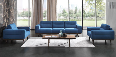 Three blue luxury fabric sofas in a living room setting with a  wooden modern coffee table in the centre.