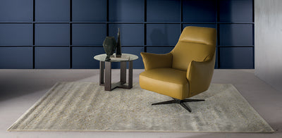 Mustard yellow leather Calma Natuzzi armchair in a blue painted room, with a side table and grey rug.